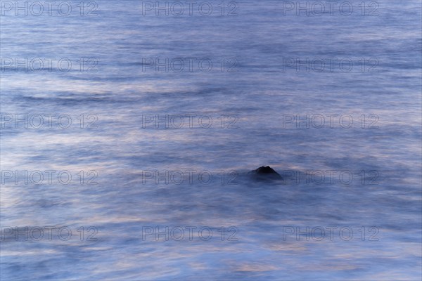 Rock poking out of the sea in the evening