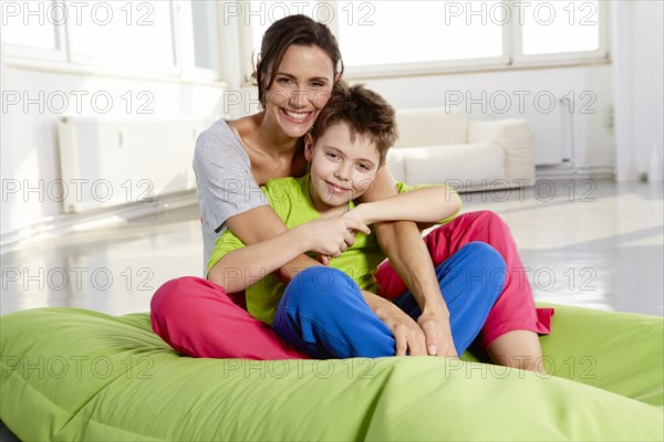 Mother and son in casual clothes sitting on a beanbag in a loft