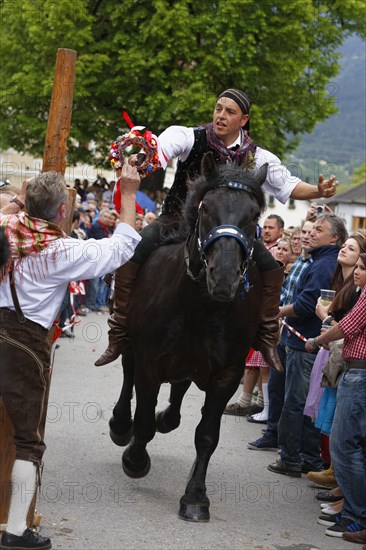 A man is handing a competitor a wreath of flowers