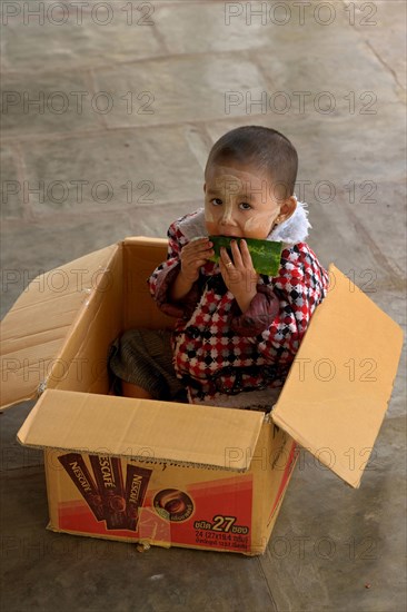 Young boy put in box to prevent him from running away while his mother is running her souvernir shop