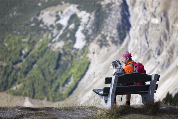 Hiker sitting on a bench next to his dog