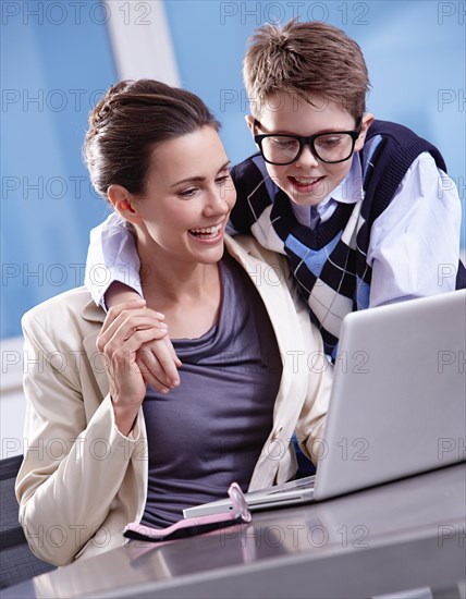 Boy with glasses puts his arm around his mother