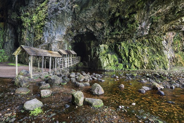 Covered bridge leading into the partly flooded with water Smoo Cave limestone cave