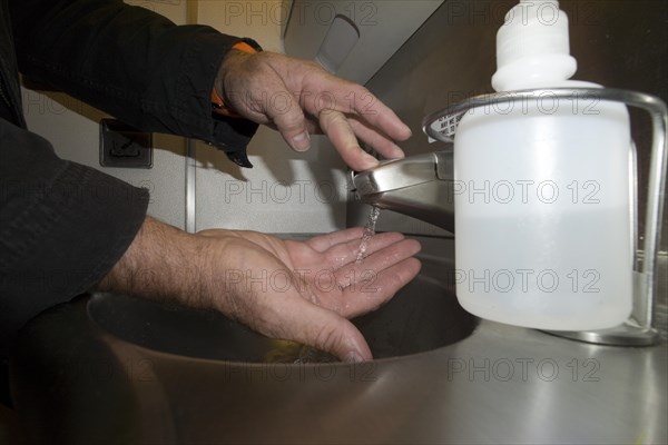 A passenger washing his hands in the lavatory of an airplane