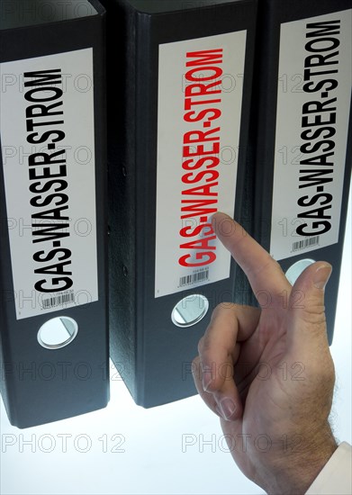 Hand pointing to a ring binder labeled Gas-Wasser-Strom