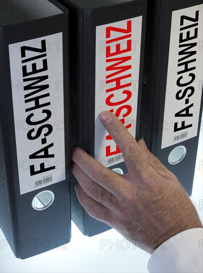 Hand reaching for file folders labeled 'FA-Schweiz'