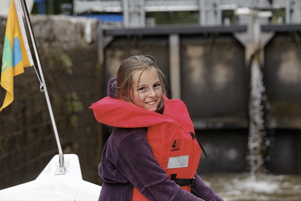 Girl wearing a life vest in a lock chamber of a rising lock