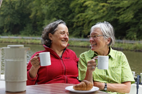 Two holidaymakers having breakfast at the rear terrace of a Penichette