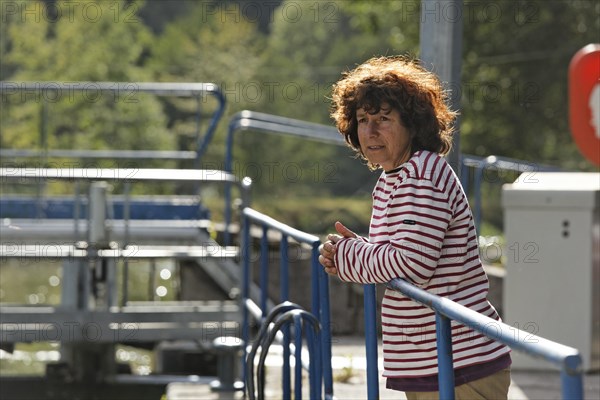 Spectator observing a houseboat passing through a lock on the Canal des Vosges