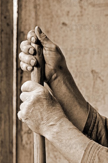 Hands marked by hard work supported on a pitchfork