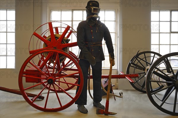 Firefighter wearing a breathing protection mask in front of a hose reel