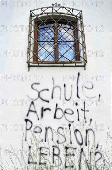 Graffiti under a barred window of a castle wall 'Schule