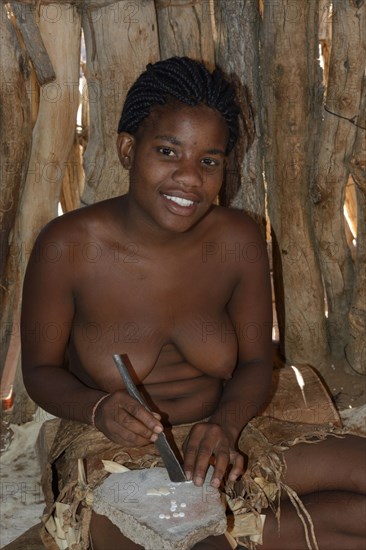 Damara woman producing buttons from mussel shells