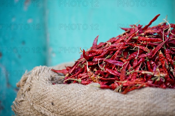 Red chillies in a sack against a turquoise wall