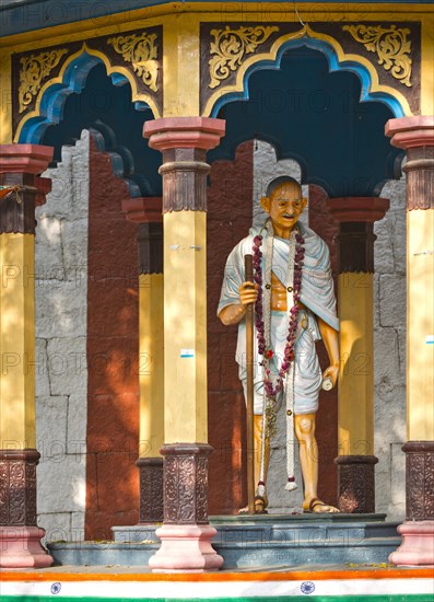 Representation of Mahatma Gandhi with walking stick in a small pavilion on the temple wall