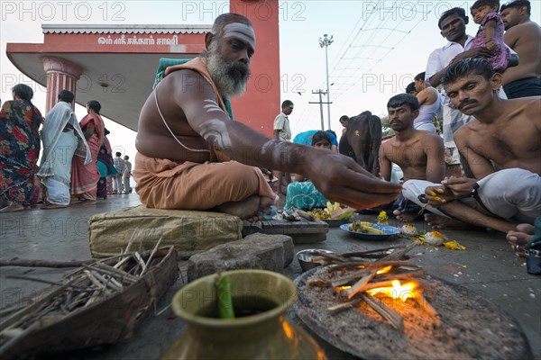 Hindu priest with pilgrims performing a fire ritual at the Ghat Agni Theertham