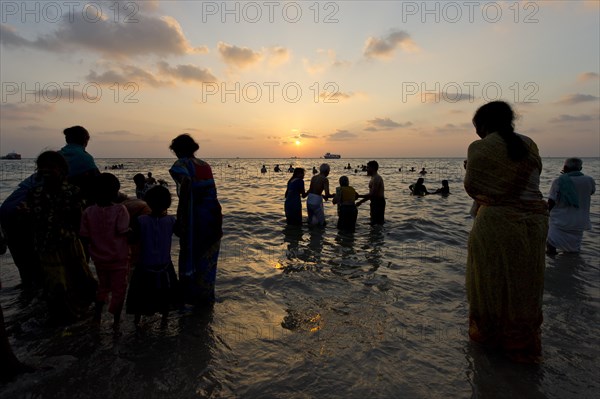 Hindu pilgrims taking a holy bath in the sea at sunrise