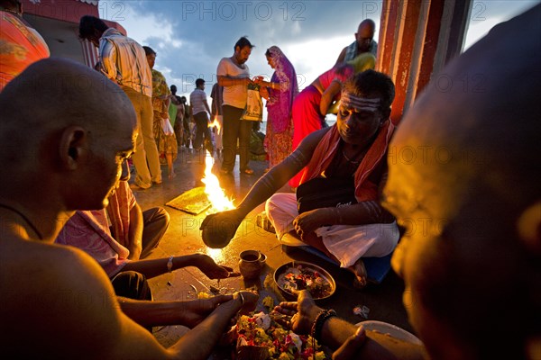 Hindu priest with pilgrims during a fire ritual at the Ghat Agni Theertham