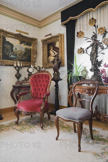 Antique chairs and furnishings adorn a living room inside a Victorian mansion