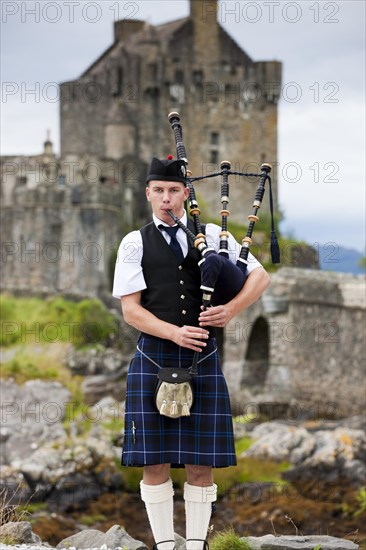 Bagpiper standing in front of Eilean Donan Castle