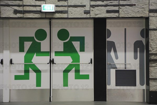 Emergency exit and toilet pictograms on doors in the station at the airport