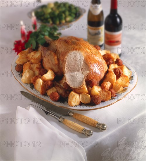 Whole roast turkey on a platter with roast potatoes