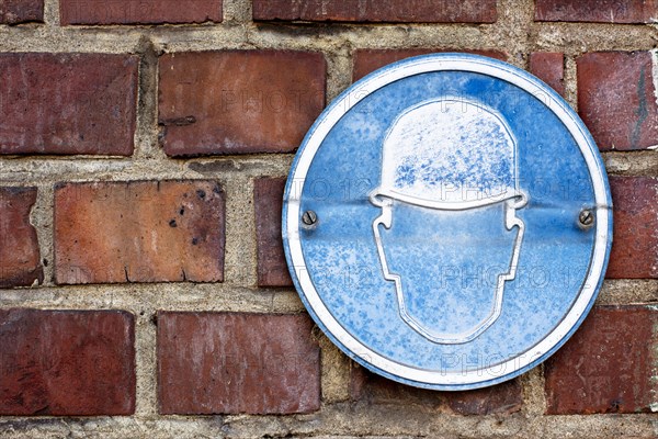 A faded sign at a construction site to wear a hard hat