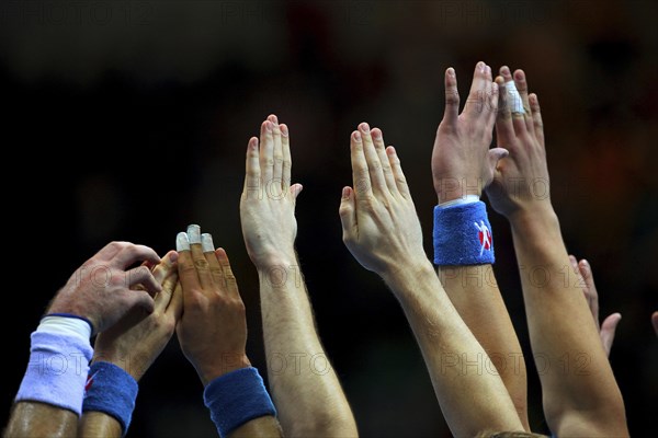 Handball players stretch their hands up to fend off a free-kick