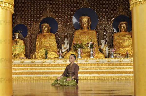 Woman meditating in front of Buddha statues