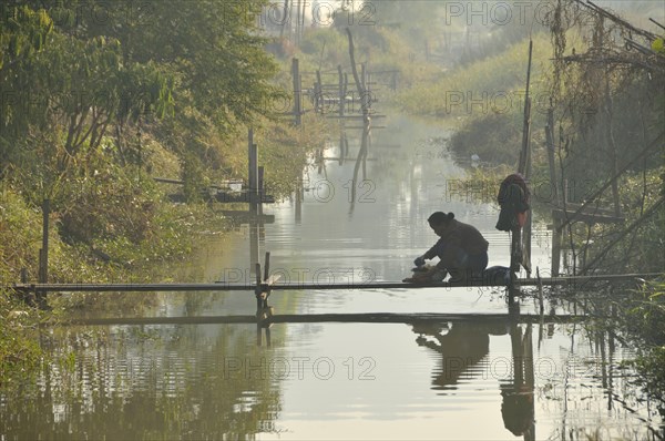 Woman washing laundry in a channel