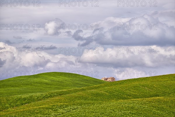 Single house between clouds and hilly fields