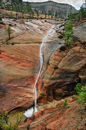 Water draining off over red Navajo sandstone rocks after a rainstorm near Canyon Overlook