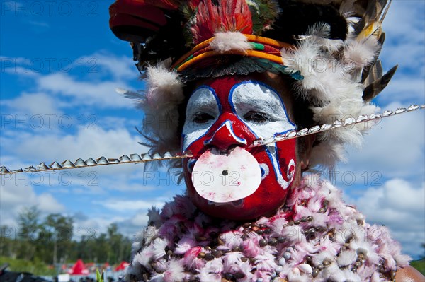 Woman in a colourfully decorated costume with face paint at the traditional sing-sing gathering