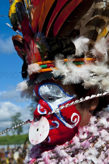 Woman in a colourfully decorated costume with face paint at the traditional sing-sing gathering