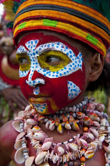 Member of a tribe in a colourfully decorated costume with face paint at the traditional sing-sing gathering