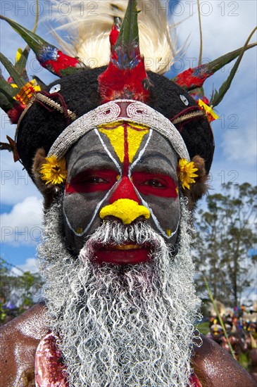 Man in a colourfully decorated costume with face paint at the traditional sing-sing gathering