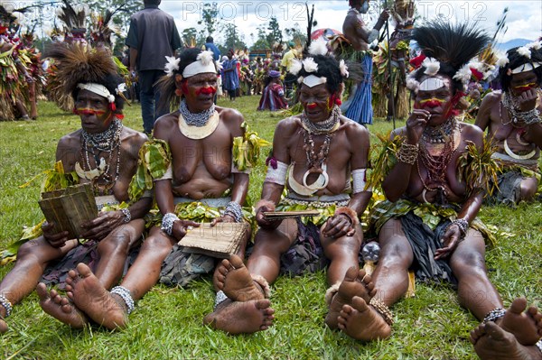 Women in colourfully decorated costumes with face paint at the traditional sing-sing gathering