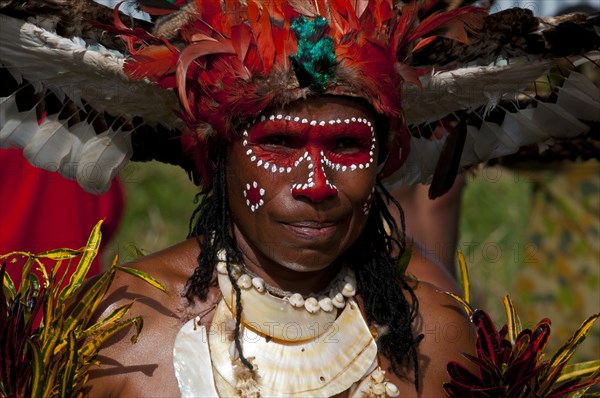 Member of a tribe in a colourfully decorated costume with face paint at the traditional sing-sing gathering