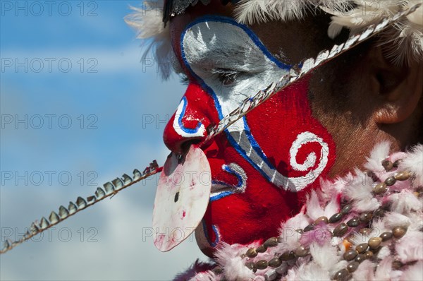 Member of a tribe in a colourfully decorated costume with face paint at the traditional sing-sing gathering