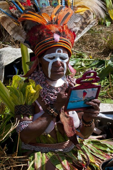 Woman applying make-up or face paint at the traditional sing-sing gathering