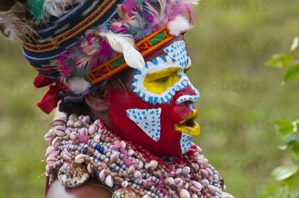 Member of a tribe in a colourfully decorated costume with face paint at the traditional sing-sing gathering