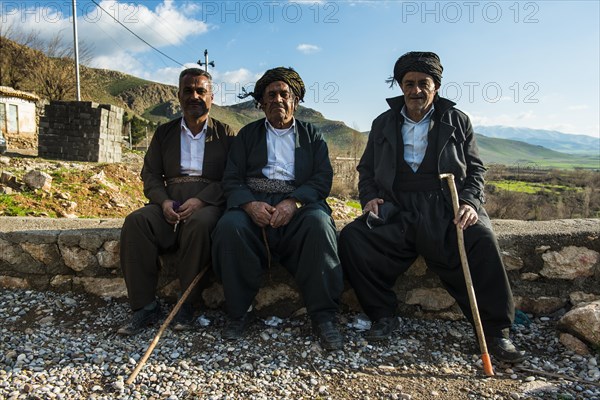 Kurdish men sitting on a wall