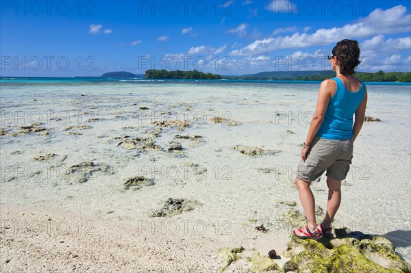 Woman standing on the beach looking towards the sea