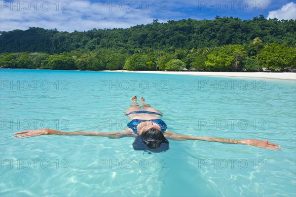 Woman floating in the water off Champagne Beach