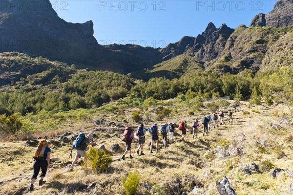 Hikers walk in single file up a slope of Col du Taibit