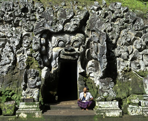 Balinese man sitting at the entrance to the Goa Gajah or Elephant Cave
