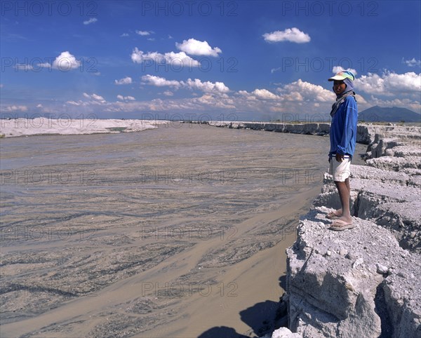 Boy standing on the bank of a mudstream