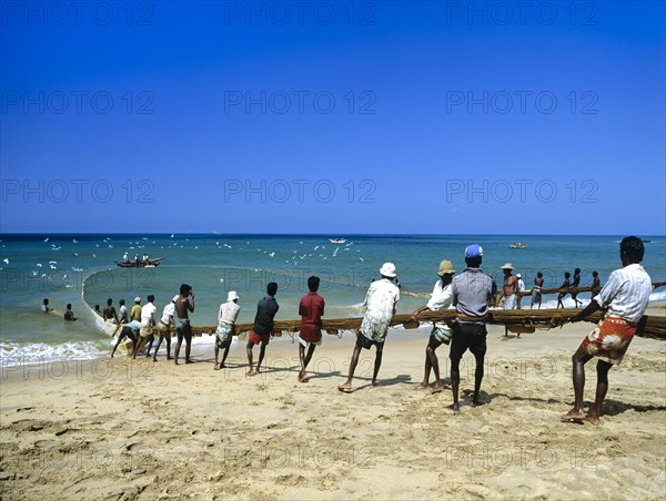 Fishermen pulling a fishing net on to the beach