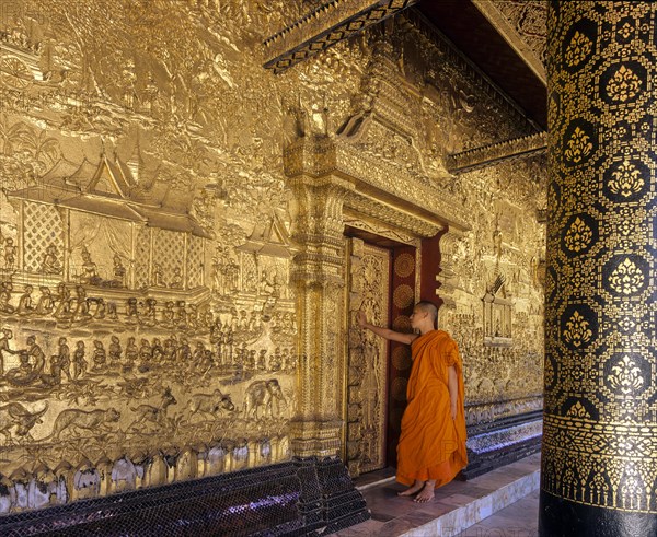Monk standing at the gilded doors of Wat Mai Temple