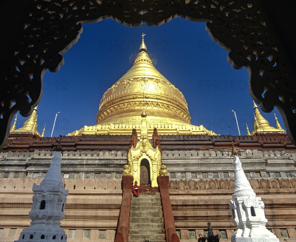Monk on the stairs of Shwezigon Pagoda with its golden chedi